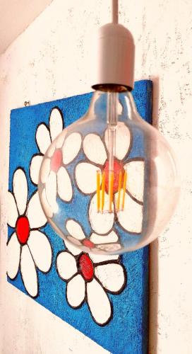 a glass light with white flowers on a blue wall at Casa GIOLE in Punta Secca