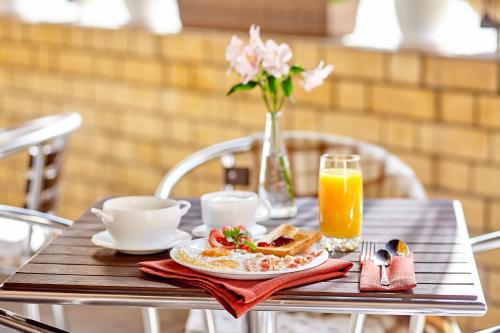 a table with a plate of breakfast food and a glass of orange juice at Stariy Dvorik on Orlovskaya in Kirov