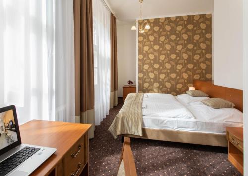 una camera con letto e computer portatile su una scrivania di Novoměstský hotel a Praga