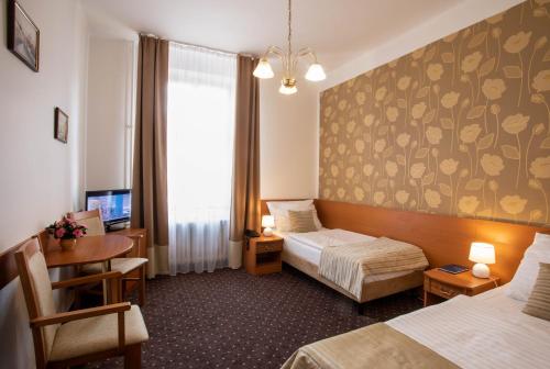a hotel room with two beds and a desk at Novoměstský hotel in Prague