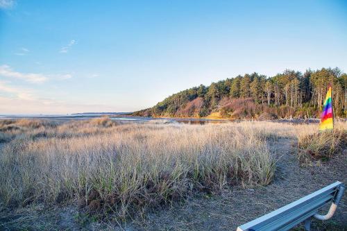 a bench sitting on a beach with a rainbow flag at Triton Condo in Moclips
