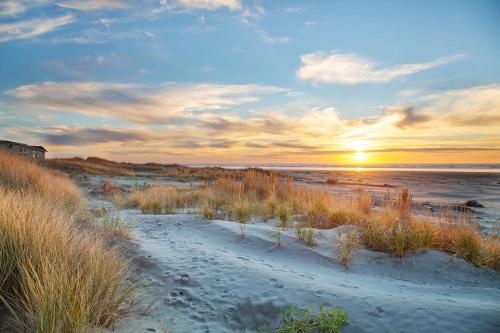 a sunset over a beach with footprints in the sand at Triton Condo in Moclips