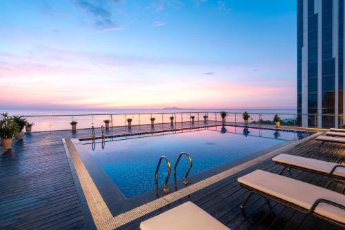 a swimming pool on the roof of a building with the ocean at Serene Beach Danang Hotel in Danang