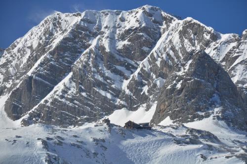 a snow covered mountain with a house in front of it at Apparthotel Bliem in Schladming