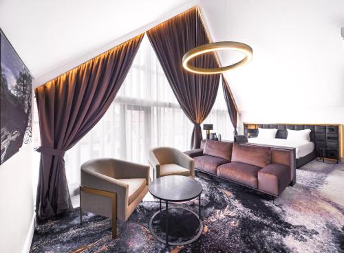 a living room with a couch and chairs and a bed at Hotel Pacai, Vilnius, a Member of Design Hotels in Vilnius