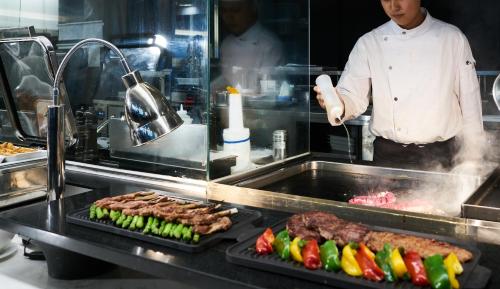 a chef preparing meat and vegetables on a grill at Phoenix Resort Pyeongchang in Pyeongchang 