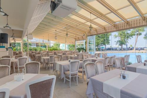 un salón de banquetes con mesas y sillas blancas en Hotel Sulina International, en Mamaia