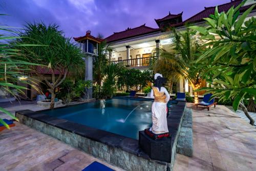 a villa with a statue in front of a swimming pool at Megacahya Bungalow in Nusa Lembongan
