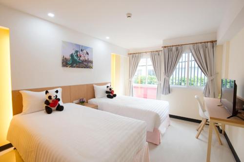 a hotel room with two beds and a television at Lucky panda Hotel in Chiang Mai