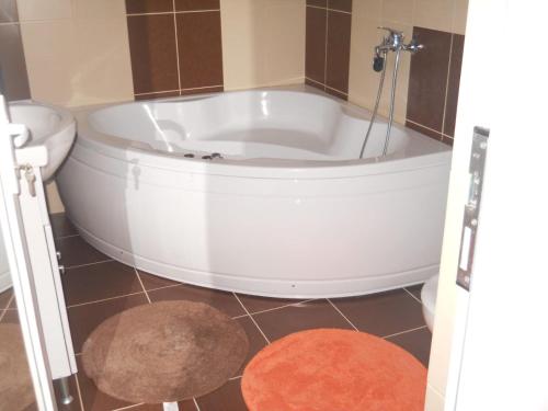 a white bath tub in a bathroom with a rug at La Curtea Argeseana in Valea Iasului