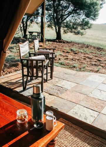 a table with a tea kettle and chairs on a patio at Cradlestone Camp in Krugersdorp