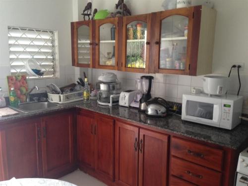 kuchnia z drewnianymi szafkami i białą kuchenką mikrofalową w obiekcie My-Places Montego Bay Vacation Home w mieście Montego Bay