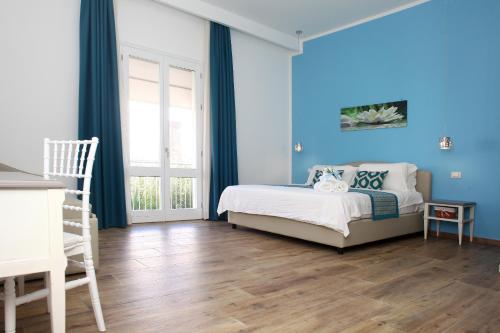 een slaapkamer met een bed met blauwe muren en houten vloeren bij b&b Za Maria in San Vito lo Capo