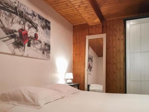 BozelにあるVacances COURCHEVEL/les 3 Valléesの白いベッドと木製の壁が備わるベッドルーム1室が備わります。