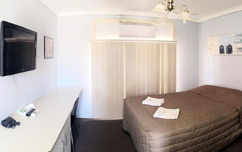 a small bedroom with a bed and a desk at Merredin Olympic Motel in Merredin