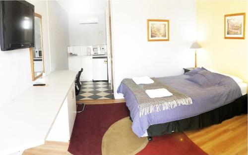 a small bedroom with a bed and a kitchen at Merredin Olympic Motel in Merredin