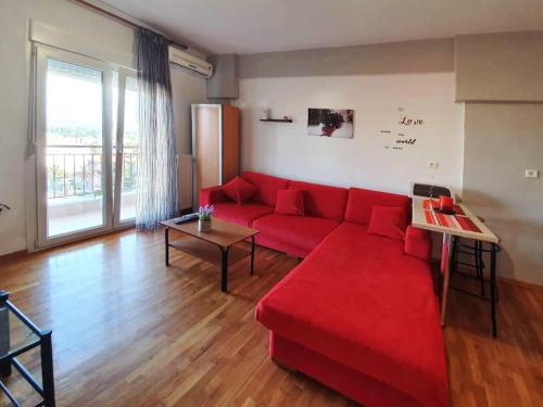 a living room with a red couch and a large window at Philippos House in Florina