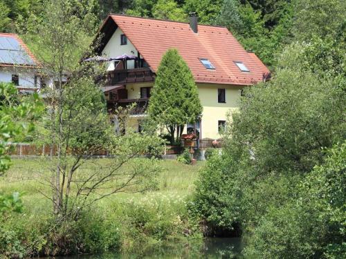 ein Haus mit rotem Dach im Wald in der Unterkunft Haus Wiesenttal in Waischenfeld