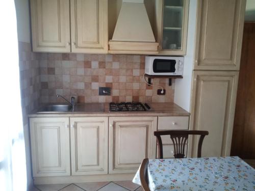 a kitchen with white cabinets and a table and a microwave at Antico Podere San Francesco in Vada