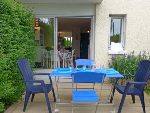 une table et des chaises bleues sur une terrasse dans l'établissement Apartment Le Garden-1 by Interhome, à Cabourg