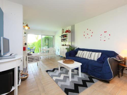 a living room with a blue couch and a table at Apartment Le Garden by Interhome in Cabourg