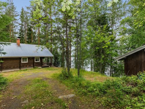 una cabaña de madera en el bosque al lado de una casa en Holiday Home Keskimökki by Interhome, en Tasapää