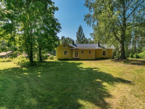 una casa amarilla en un patio con árboles en Holiday Home Rauhalinna by Interhome en Paatela