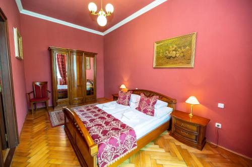 イチーンにあるGrand Hotel Prahaのピンクの壁のベッドルーム1室(大型ベッド1台付)