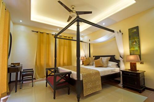 a bedroom with a canopy bed and a desk at The Palm Seychelles in Bel Ombre