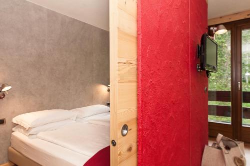 a bedroom with a red door with a bed at Ambiez Residencehotel in Madonna di Campiglio