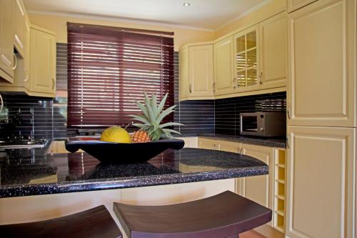 a kitchen with a bowl of fruit on a counter at The Palm Seychelles in Bel Ombre