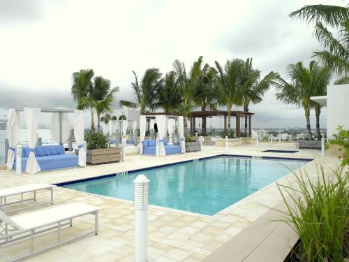 a pool on the roof of a hotel with palm trees at Grand Beach Hotel Surfside in Miami Beach