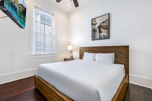 a bedroom with a large white bed and a window at Fabulous Cottages with City Views in New Orleans