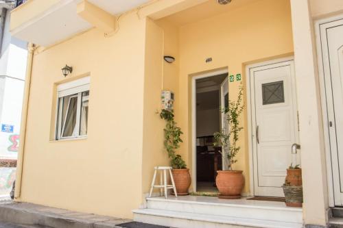 ein gelbes Haus mit Topfpflanzen vor der Haustür in der Unterkunft Elizabeth's Place in Iraklio