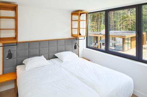 een slaapkamer met 2 witte bedden en een raam bij Landgoed Bergvliet in Oosterhout