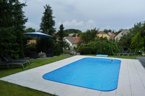 a swimming pool in a yard with chairs and an umbrella at Penzion Stranny in Stranný