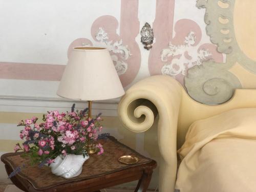 a table with a lamp and a vase with flowers on it at Villa il Galero in Asolo
