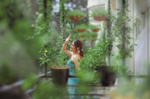 a woman standing in a garden with her hand up at Thang Long Opera Hotel in Hanoi