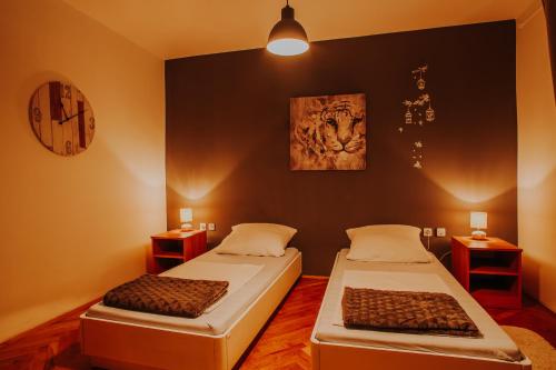 dwa łóżka w pokoju z zegarem na ścianie w obiekcie Apartmani Marin w mieście Vukovar