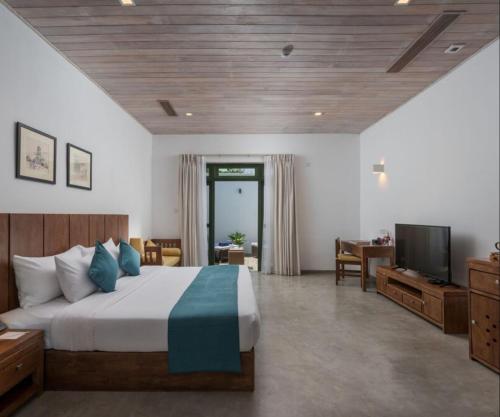 a hotel room with a bed and a television at Regenta Arie Lagoon Negombo in Negombo
