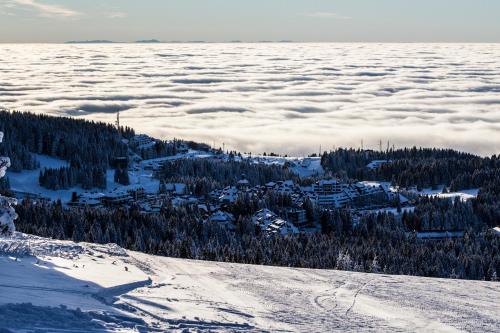 a view from the top of a snowy mountain with clouds at Rtanj Kopaonik Eco Resort & Spa in Kopaonik