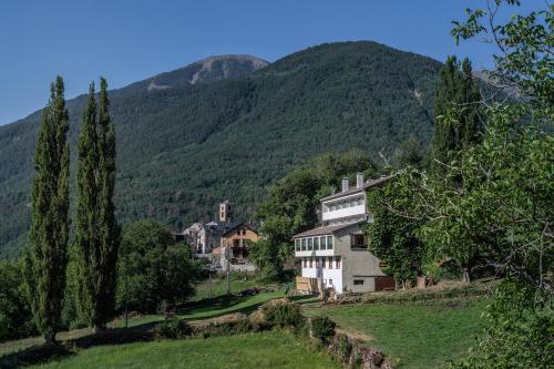 a house on a hill with mountains in the background at Hotel de Montaña El Mirador in Broto