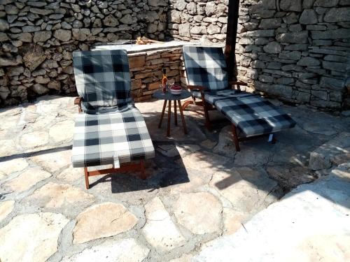 two chairs and a table in front of a stone wall at Pirate's Nest Stone House in Korčula