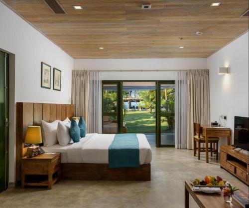 een slaapkamer met een bed, een bureau en een televisie bij Regenta Arie Lagoon Negombo in Negombo