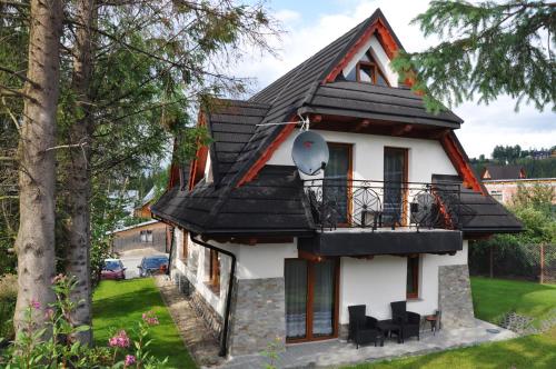 una pequeña casa blanca con techo negro en Apartamenty JSZI en Zakopane