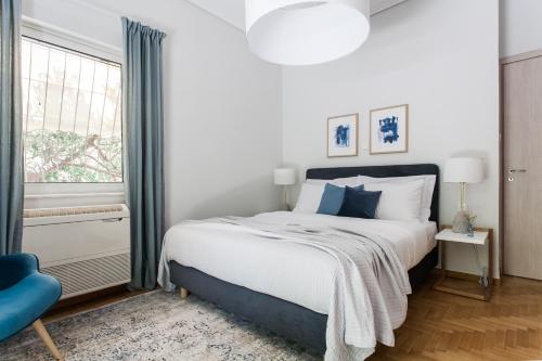 um quarto com uma cama grande e uma cadeira azul em Bright 2BD Apartment in Psychiko by UPSTREET em Atenas