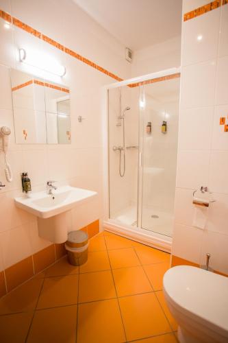 an orange and white bathroom with a sink and shower at Resort Malevil in Jablonné v Podještědí