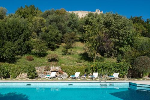 a pool with chairs and a hill in the background at Villa il Galero in Asolo