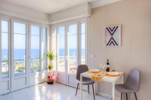 une salle à manger avec une table, des chaises et des fenêtres dans l'établissement #23 Henry IV Vue Panoramique Mer AC & Bright, à Nice