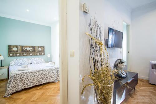 a bedroom with a bed and a vase of flowers at Apartamentos Dali Madrid in Madrid